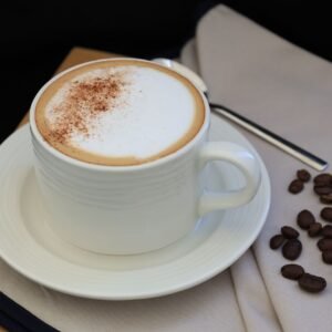 A cozy composition of a cappuccino cup with sprinkled cinnamon and scattered coffee beans on the side.