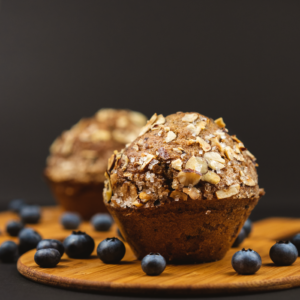 Close-up of freshly baked blueberry muffins topped with sugar and nuts, surrounded by fresh blueberries.